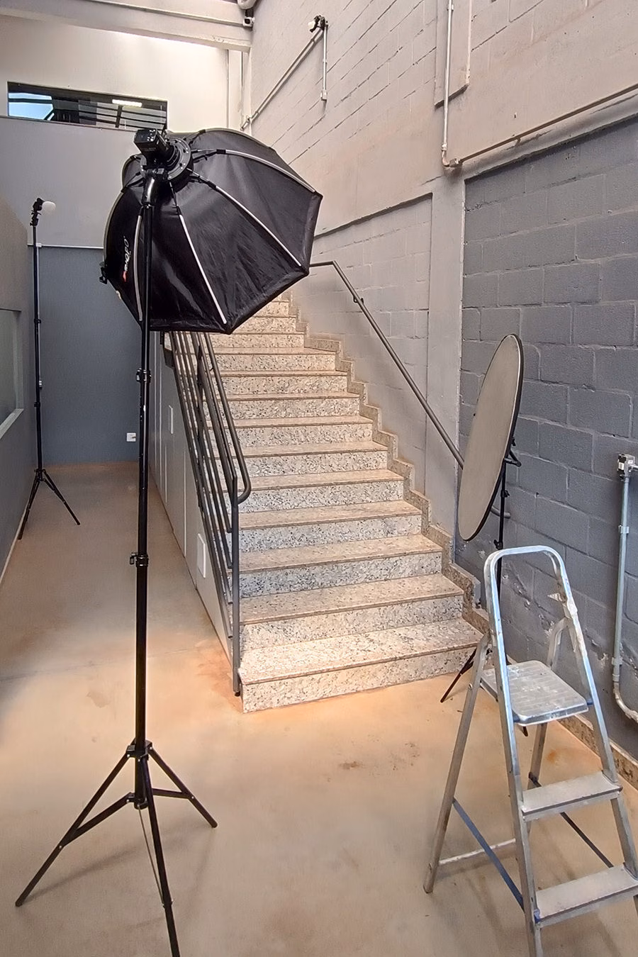 Estúdio montado na sede da Rysax do Brasil, com softbox e refletor posicionados na escada